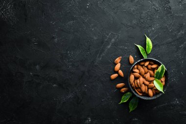 Siyah bir arka plan üzerinde bir kase içinde Fındık Badem. Üst te. Metniniz için boş alan.