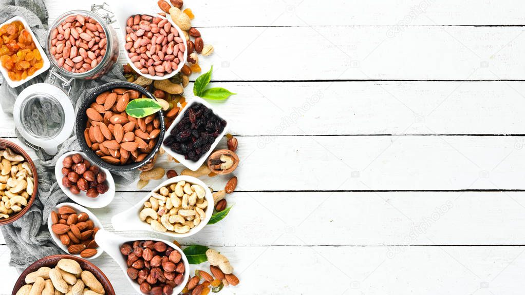 Assorted nuts on a white wooden background. Top view. Free space for your text.
