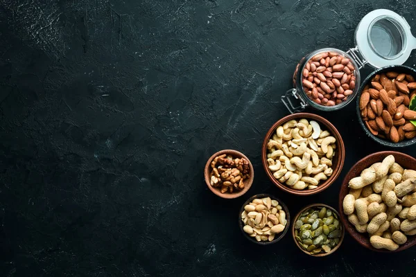 Assorted nuts on the old black background. Top view. Free space for your text.