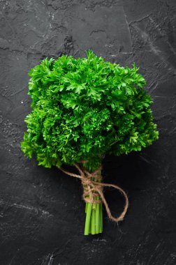 Taze yeşil maydanoz. Baharatlar ve otlar. Siyah taş bir arka plan üzerinde. Üst te. Metniniz için boş alan.