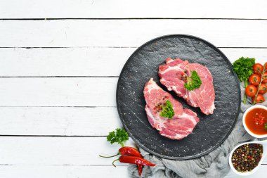 Çiğ domuz bifteği. Taze et. Bir tabak baharat ve ot. Üst te. Metniniz için boş alan.