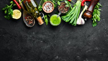 Green parsley sauce, olive oil and spices. Ingredients for chimichurri sauce. On a black background. Top view. free space for your text. clipart