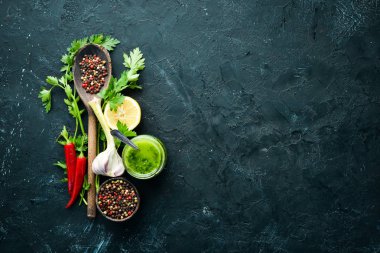 Yeşil maydanoz sosu, zeytinyağı ve baharatlar. Chimichurri sosu için malzemeler. Siyah bir arka plan üzerinde. Üst te. metniniz için boş alan.
