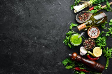 Yeşil maydanoz sosu, zeytinyağı ve baharatlar. Chimichurri sosu için malzemeler. Siyah bir arka plan üzerinde. Üst te. metniniz için boş alan.