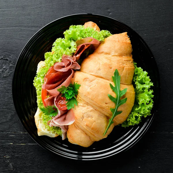 Eski ahşap arka plan prosciutto dilimleri ile Sandviç. Kruvasan Kahvaltı. Üst te. Metniniz için boş alan.