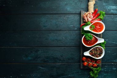 Ahşap bir arka plan üzerinde kırmızı soslar seti. Ketçap, barbekü sosu, domates sosu. Üst te. Metniniz için boş alan.