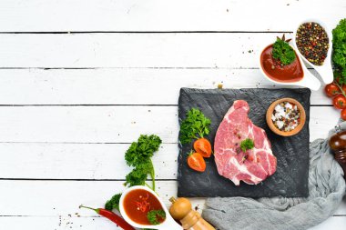 Tahtada çiğ biftek var. Et. Baharatve otlarla eski masada. Üst te. Metniniz için boş alan.