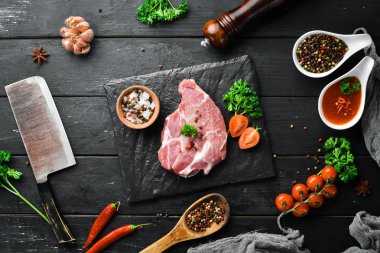 Tahtada çiğ biftek var. Et. Baharatve otlarla eski masada. Üst te. Metniniz için boş alan.