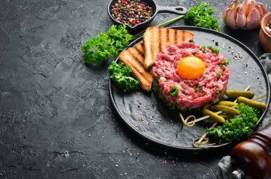 Çiğ yumurta sarısı, salatalık turşusu ve soğan ile Sığır biftek tartar. Fransız mutfağı. Üst te. Metniniz için boş alan.