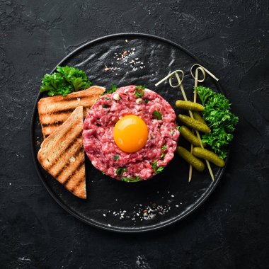 Çiğ yumurta sarısı, salatalık turşusu ve soğan ile Sığır biftek tartar. Fransız mutfağı. Üst te. Metniniz için boş alan.