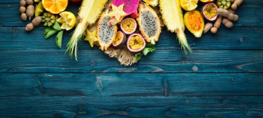 Tropikal meyveler - mavi bir arka plan üzerinde tutku meyve, ananas, ejderha meyve, kivi ve kaktüs.