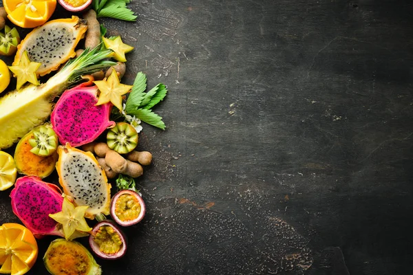 トロピカルフルーツ 茶色の背景にパッションフルーツ パイナップル ドラゴンフルーツ キウイとサボテン トップビュー — ストック写真