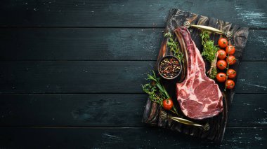 Siyah arka planda çiğ kuru biftek kovboy. Tomahawk bifteği. Barbekü üst görünümü. Metin için boş alan.