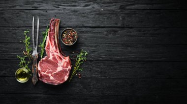 Siyah arka planda çiğ kuru biftek kovboy. Tomahawk bifteği. Barbekü üst görünümü. Metin için boş alan.