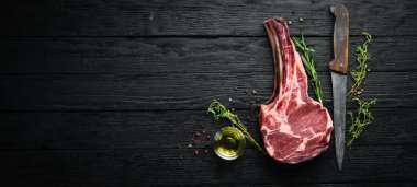 Siyah arka planda çiğ kuru biftek kovboy. Tomahawk bifteği. Barbekü üst görünümü. Metin için boş alan.