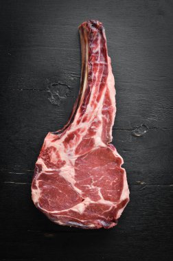 Siyah arka planda çiğ kuru biftek kovboy. Tomahawk bifteği. Barbekü üst görünümü. Metin için boş alan.