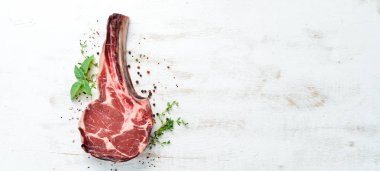 Beyaz ahşap arka planda çiğ kovboy bifteği ve baharatlar. Bbq Top görünümü. Metin için boş alan.