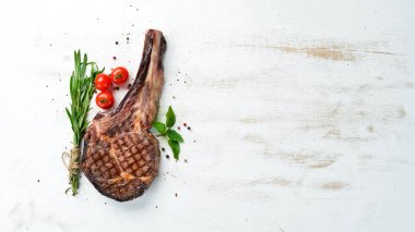 Beyaz ahşap arka plan üzerinde bir kemik üzerinde ızgara biftek. Barbekü. Üst te. Metin için boş alan.