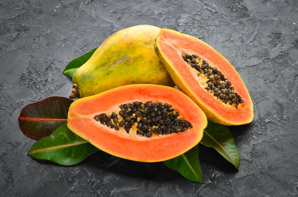 Fresh papaya on a black stone background. Tropical Fruits. Top view. Free space for text.