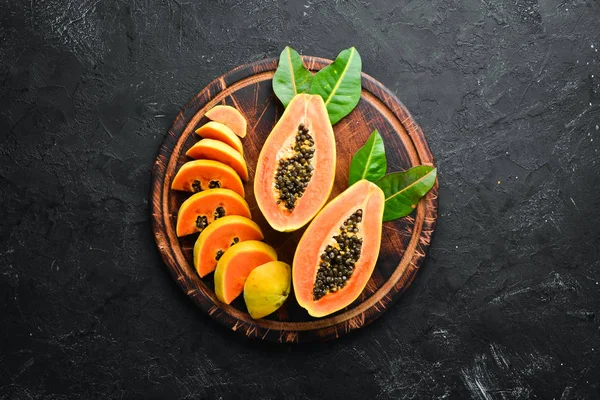 Fresh papaya on a black stone background. Tropical Fruits. Top view. Free space for text.