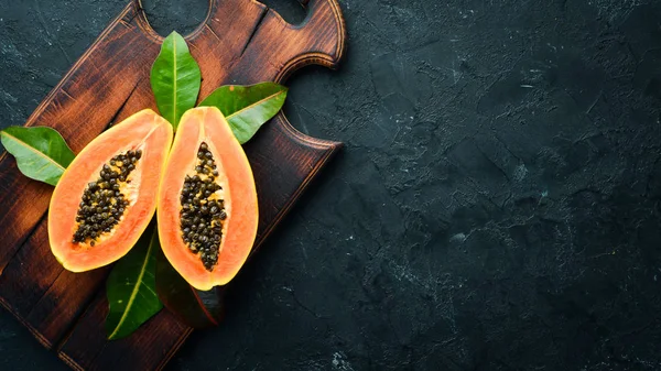 Fresh papaya on a black stone background. Tropical Fruits. Top view. Free space for text.