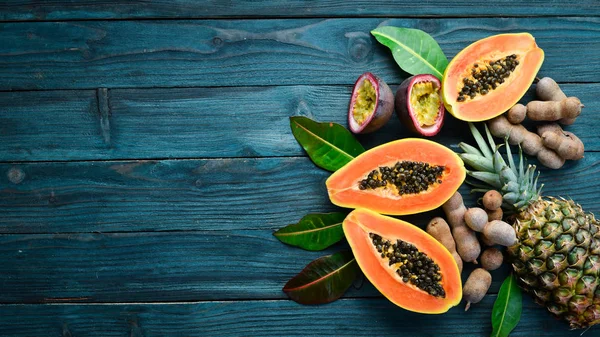 Tropikal meyveler, tatlı papaya, mavi ahşap arka plan üzerinde çiğ vegan gıda. Üst te. Metin için boş alan.