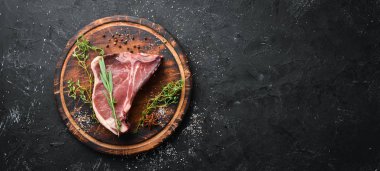 Siyah taş masada çiğ t-kemik biftek. Üst te. Metin için boş alan.