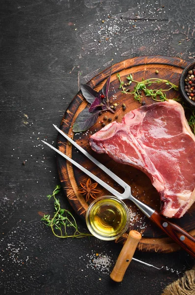 Tahta bir masada çiğ t-kemik biftek. Üst te. Metin için boş alan.