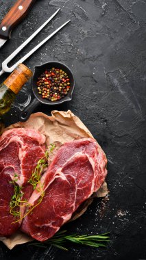 Çiğ Biftek Ribeye. Siyah taş bir masanın üzerinde. Üst te. Metniniz için boş alan.