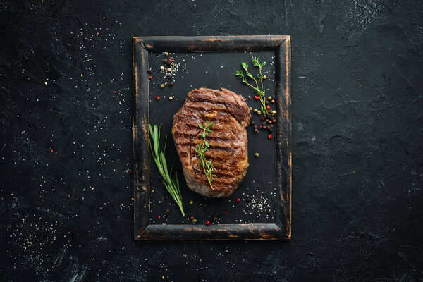 Grilled beef steak medium rare on a black stone table. Top view. Free space for your text.
