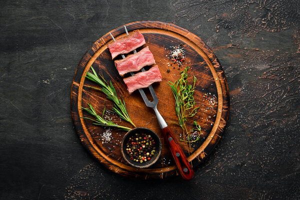 Juicy Steak on the fork with herbs and spices. Top view. Free space for your text.