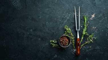 Siyah bir taş masada et, baharat ve otlar için çatal. Üst te. Metniniz için boş alan.