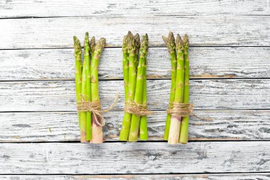 Beyaz ahşap arka plan üzerinde taze yeşil kuşkonmaz. Sağlıklı yiyecekler. Üst te. Metniniz için boş alan.