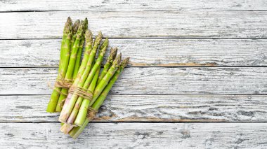 Beyaz ahşap arka plan üzerinde taze yeşil kuşkonmaz. Sağlıklı yiyecekler. Üst te. Metniniz için boş alan.