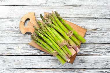 Beyaz ahşap arka plan üzerinde taze yeşil kuşkonmaz. Sağlıklı yiyecekler. Üst te. Metniniz için boş alan.