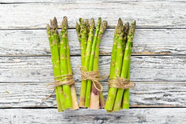 Beyaz ahşap arka plan üzerinde taze yeşil kuşkonmaz. Sağlıklı yiyecekler. Üst te. Metniniz için boş alan.