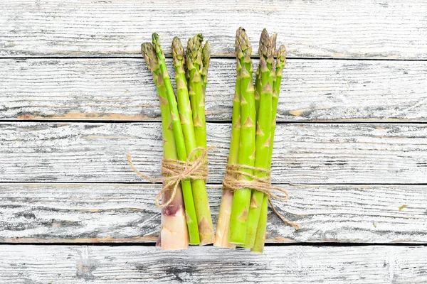 Beyaz ahşap arka plan üzerinde taze yeşil kuşkonmaz. Sağlıklı yiyecekler. Üst te. Metniniz için boş alan.