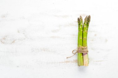 Beyaz ahşap arka plan üzerinde taze yeşil kuşkonmaz. Sağlıklı yiyecekler. Üst te. Metniniz için boş alan.