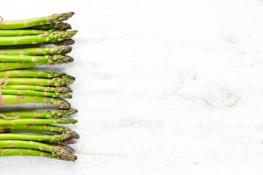 Beyaz ahşap arka plan üzerinde taze yeşil kuşkonmaz. Sağlıklı yiyecekler. Üst te. Metniniz için boş alan.