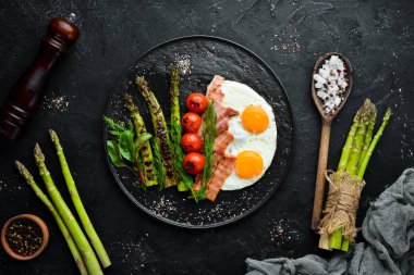 Kahvaltı. Kuşkonmaz, yumurta, pastırma ve kiraz domates. Sağlıklı yiyecekler. Üst te. Metniniz için boş alan.