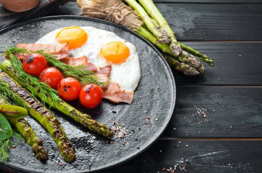 Kahvaltı. Kuşkonmaz, yumurta, pastırma ve kiraz domates. Sağlıklı yiyecekler. Üst te. Metniniz için boş alan.