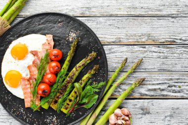 Kahvaltı. Kuşkonmaz, yumurta, pastırma ve kiraz domates. Sağlıklı yiyecekler. Üst te. Metniniz için boş alan.