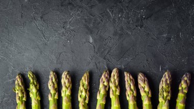 Siyah taş arka plan üzerinde taze yeşil kuşkonmaz. Üst te. Metniniz için boş alan.