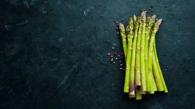 Siyah taş arka plan üzerinde taze yeşil kuşkonmaz. Üst te. Metniniz için boş alan.