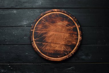 Old Wooden kitchen board on a black background. Top view. Free space for your text. clipart