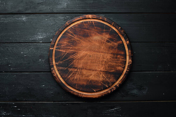 Old Wooden kitchen board on a black background. Top view. Free space for your text.