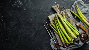 siyah bir arka plan üzerinde taze yeşil kuşkonmaz demetleri. Sağlıklı yiyecekler. Üst te. Metniniz için boş alan.