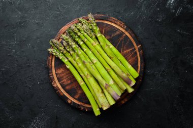 siyah bir arka plan üzerinde taze yeşil kuşkonmaz demetleri. Sağlıklı yiyecekler. Üst te. Metniniz için boş alan.