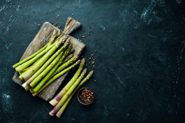 siyah bir arka plan üzerinde taze yeşil kuşkonmaz demetleri. Sağlıklı yiyecekler. Üst te. Metniniz için boş alan.
