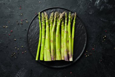 siyah bir arka plan üzerinde taze yeşil kuşkonmaz demetleri. Sağlıklı yiyecekler. Üst te. Metniniz için boş alan.